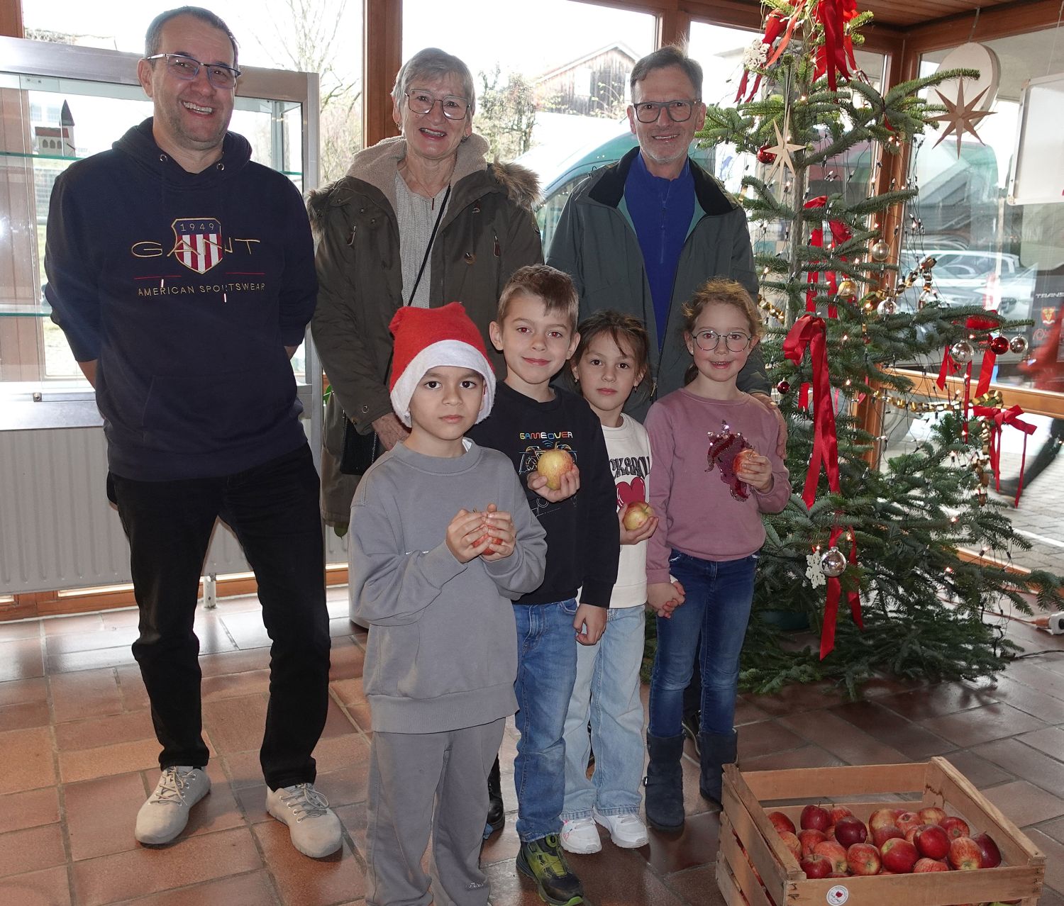 3 Erwachsene Und kinder neben einer Kiste mit Äpfeln, Kinder haben Äpfel in der Hand